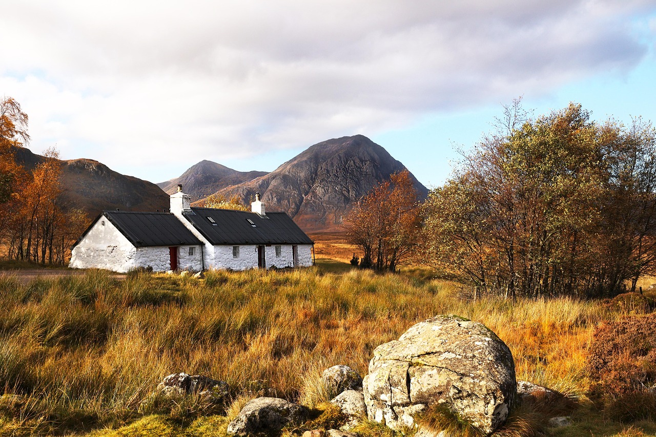 A cottage among autumn trees with mountains rising behind it